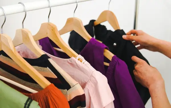 Roupas femininas coloridas penduradas em cabides de madeira, sendo utilizadas para esclarecer o que vender na shopee com baixo investimento